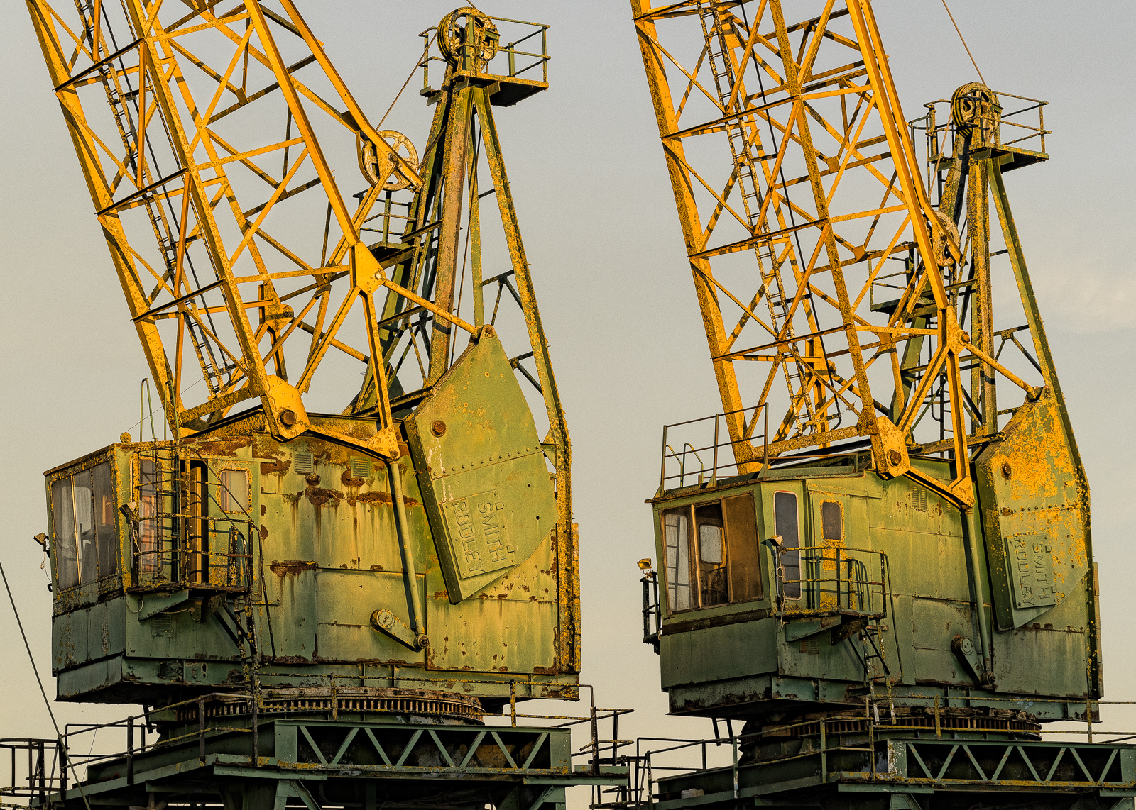 Two disused green and yellow cranes standing in Sharpness Docks