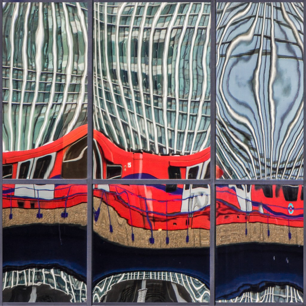 Reflections of a red DLR train in a Canary Wharf office window