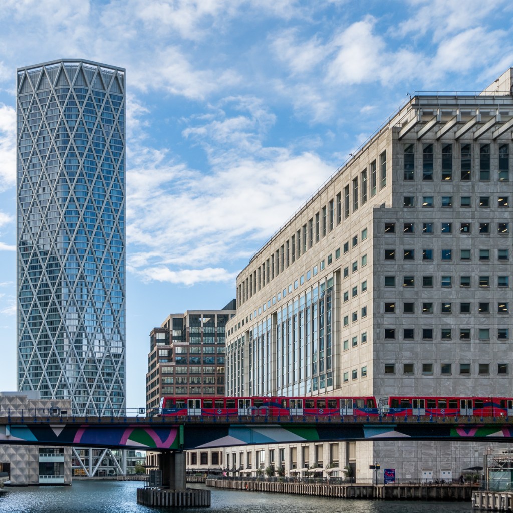 A red DLR train makes a splash of red against the urban backdrop of Canary Wharf
