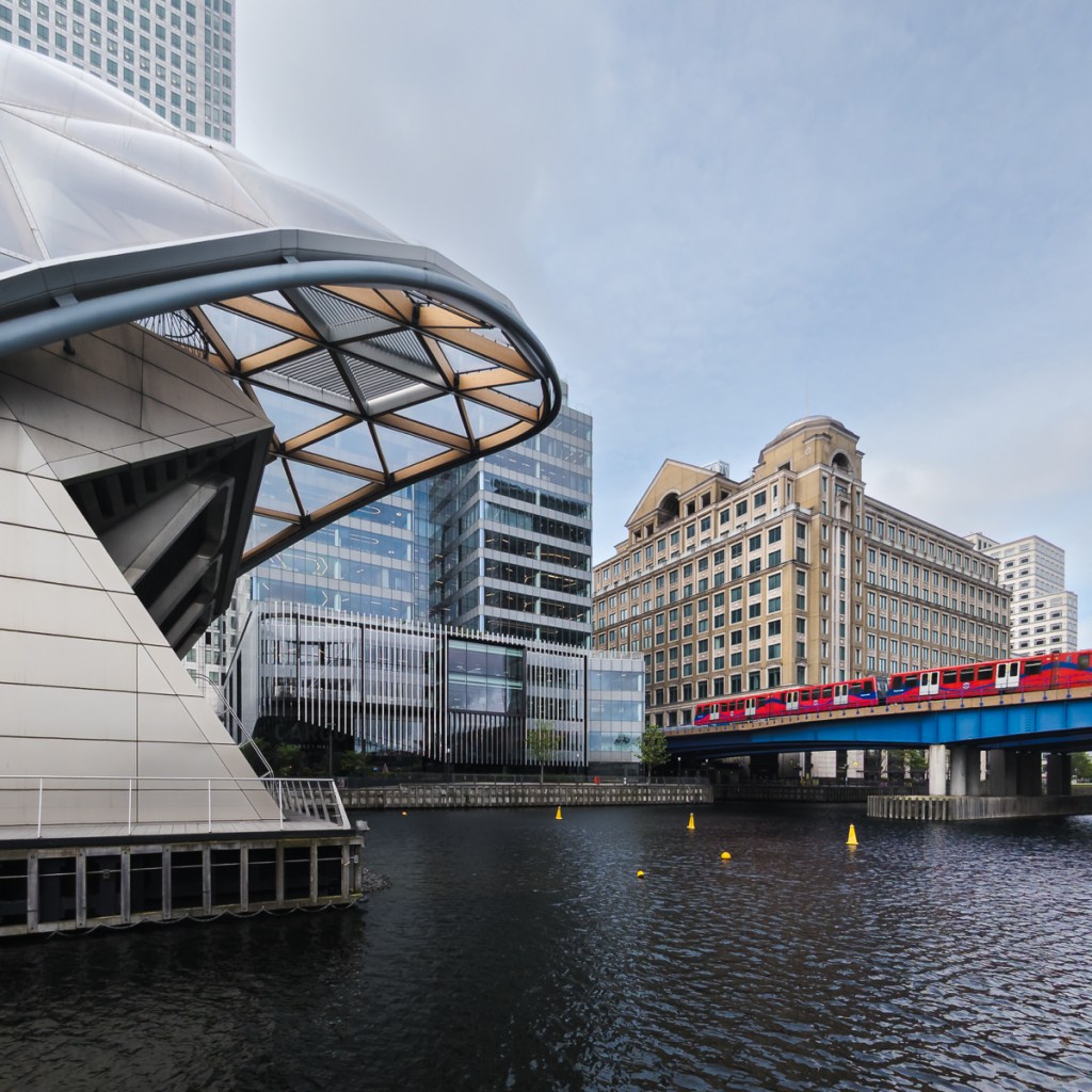 A red DLR train makes a splash of red against the urban backdrop of Canary Wharf