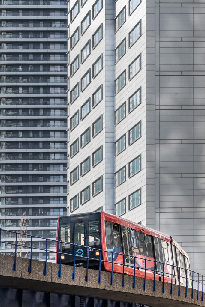 A red DLR train makes a splash of red against the urban backdrop of Canary Wharf
