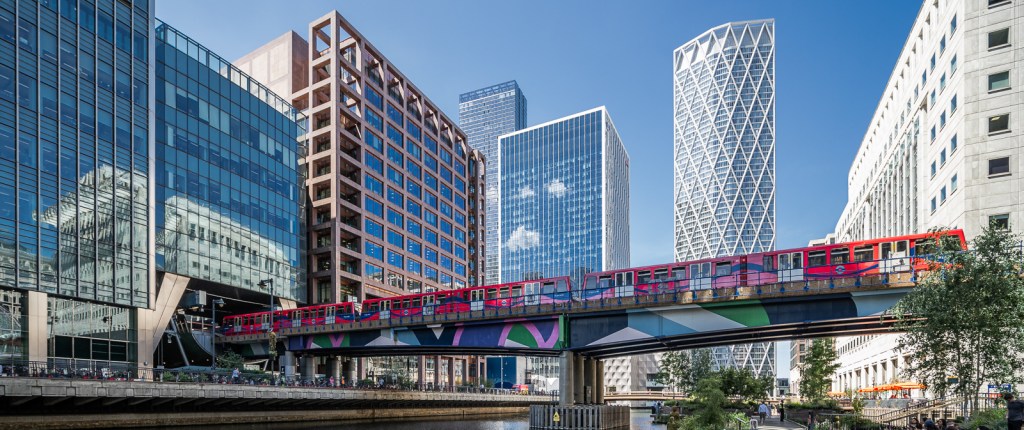 A red DLR train makes a splash of red against the urban backdrop of Canary Wharf