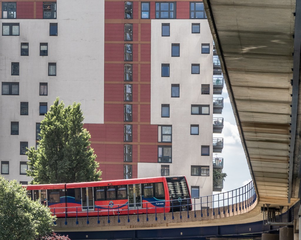 A red DLR train makes a splash of red against the urban backdrop of Canary Wharf