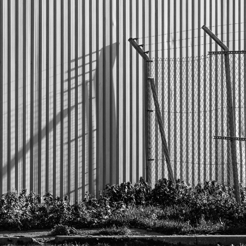 Shadows of barbed wire fencing on a modern steel building